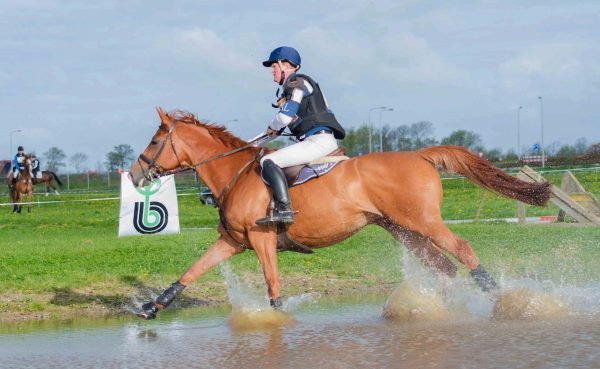 ruiter en paard tijdens de paardencross door de waterbak van NHHT